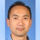 Man with short dark hair wearing a blue shirt